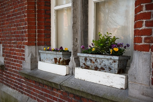 Vintage windowsill with flower boxes on a brick wall, showing signs of wear and rustic charm.
