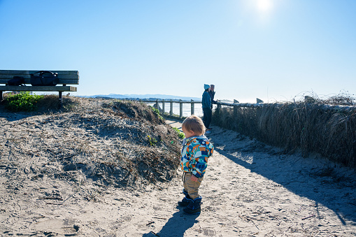 A one year old boy has fun exploring a sandy spot at a lookout overlooking the Pacific Ocean while on a road trip with his family along the Oregon Coast.