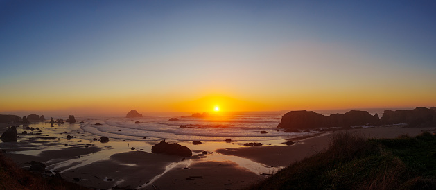 Panoramic view of a vibrant sunset over the Pacific Ocean shot from a scenic viewpoint in Bandon, Oregon.