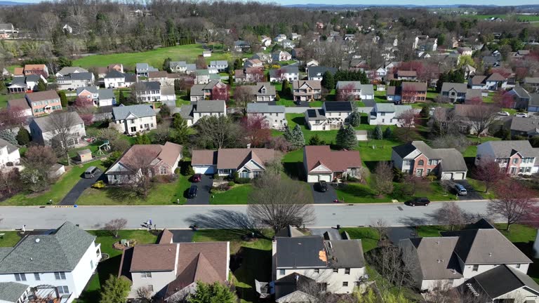 Beautiful american suburb neighborhood with one family house in spring season. Sunny day with green garden at sunlight. Aerial lateral wide shot.