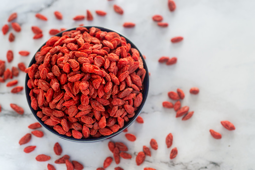 Dried  goji berries in ceramic bowl on marble table background.
