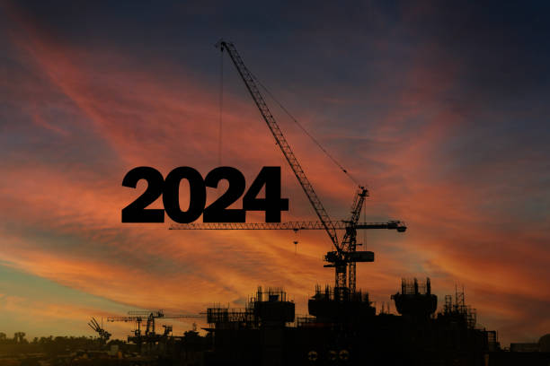 istock Construction site with crane is a tall, long-arm machine, intended for use in 2024. Silhouette of staff as a team to prepare to welcome the 2024. 2121416631