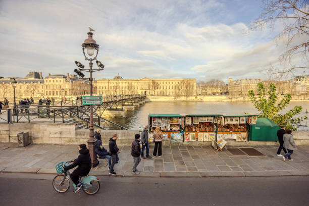 View of an art vendor with Pont des Arts on the left from the top deck of a hop-on hop-off Tootbus along Seine River in Paris, France, on Christmas Eve 2023