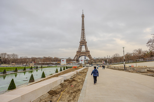 A tourist walking beside Fontaine du Jardin du Trocadero toward Eiffel Tower on Christmas Day 2023