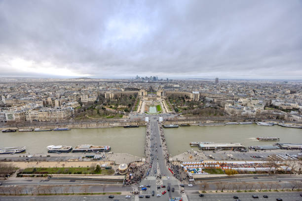 The views from the second floor of Eiffel Tower on a rainy and cloudy Christmas Day 2023, with cruise boat on Seine River, Palais de Chaillot further back, and the high risers of La Defense far back