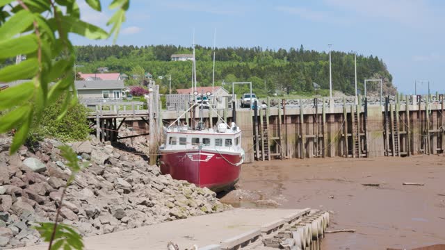Slow motion shot of a commercial fishing boat that is beached during low tide at a small pier located in a small village in the Bay of Fundy, New Brunswick, Canada shot in 4k.