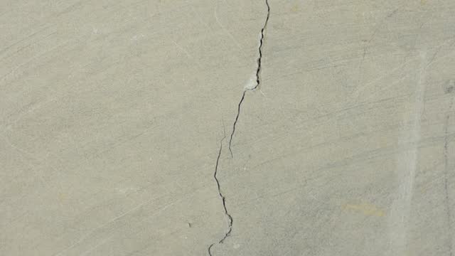 the finger points to a crack in the concrete wall. Destruction of a concrete structure