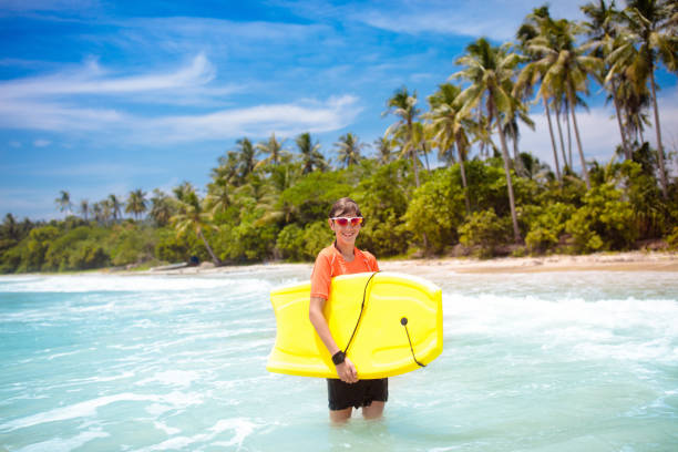 istock Child surfing on tropical beach. Surfer in ocean. 2121644125
