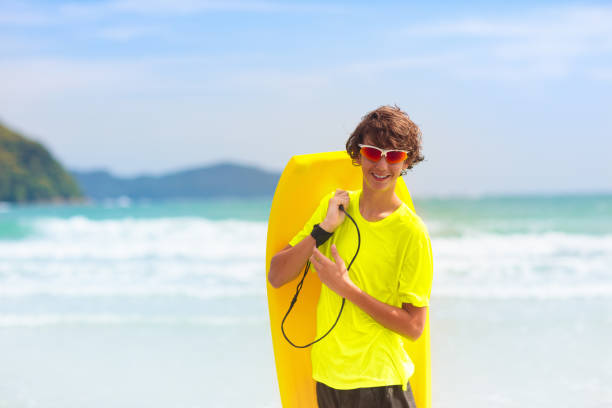Teenage Latino boy having fun swimming and riding his skimboard in the crashing ocean waves.Taken off the coast of La Selva Beach, Santa Cruz, California, USA
