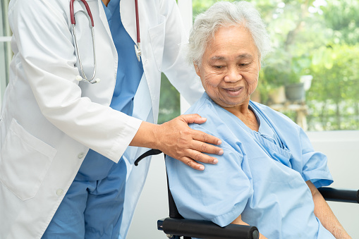 Doctor help and care Asian senior woman on wheelchair at hospital.