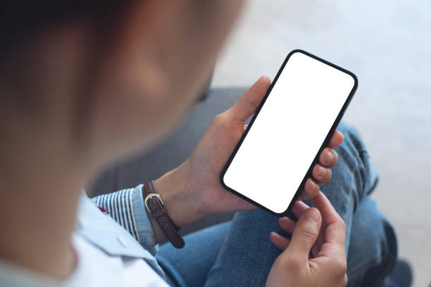 istock Mockup, woman's hands holding mobile phone with blank screen in coffee shop, over shoulder view 2121658049