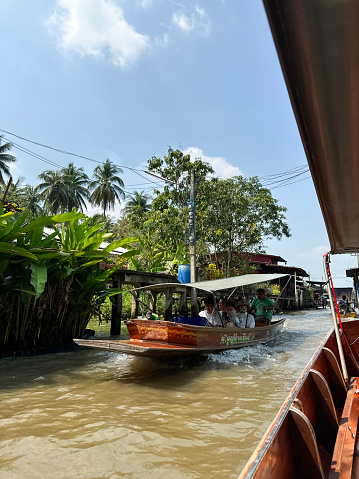 Bangkok, Thailand - February, 16 2024: Stock photo showing  view of river cruise tour boats touring the canals and waterways of Khlong Damnoen Saduak a canal link to Tha Chin and Mae Klong rivers.