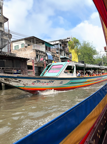 Bangkok, Thailand - February, 15 2024: Stock photo showing  view of river cruise tour boats touring the canals and waterways of Khlong Damnoen Saduak a canal link to Tha Chin and Mae Klong rivers.