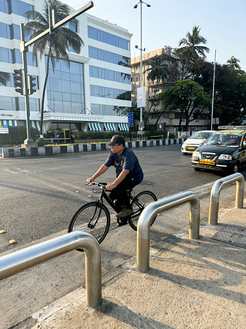 Mumbai, Maharashtra, India - March 16, 2024: Stock photo showing close-up view of traffic including a bicycle being ridden amongst cars and motorbikes in retail district.