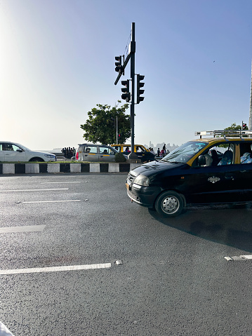 Marine Drive, Mumbai, Maharashtra, India - March, 15 2024: Stock photo showing close-up view of multilane highway running along coastline at Marine Drive, Mumbai, India. Traffic driving off from stop sign after it has changed to go.