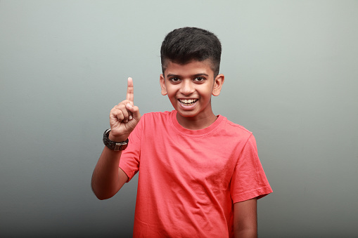 Portrait of a cheering Indian ethnic smart boy with hand gesture