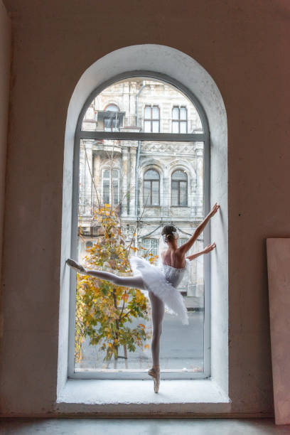 istock Ballerina poses en pointe, white tutu within an arched window frame, juxtaposing the refined beauty 2121738977