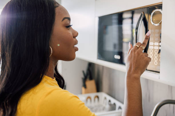 istock Daily routine, young woman preparing food on microwave 2121795928