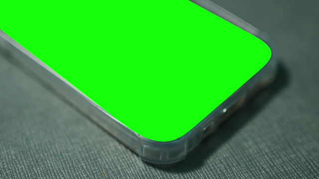 Smart phone with green screen on the table. No people.