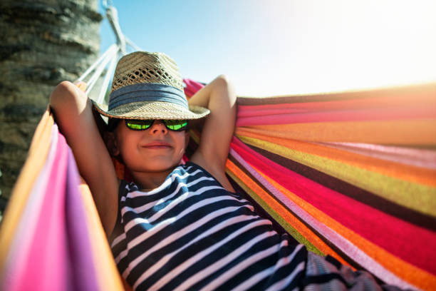 istock Little boy resting on hammock on beach 2121850326