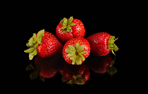 istock Four strawberries rest on black surface, vibrant produce from natures bounty 2121860784