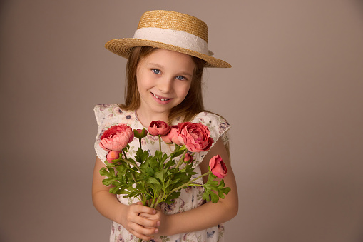 Little girl with a straw hat holding a bouquet of flowers