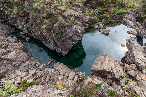 The emerald waters of the Fairy Pools glisten from above, set in a rocky embrace on the Isle of Skye, a natural jewel in the Scottish wilds