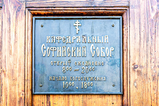 Veliky Novgorod, Russia - August 23, 2019: Signboard and opening hours of the Saint Sophia Cathedral on the front wooden door