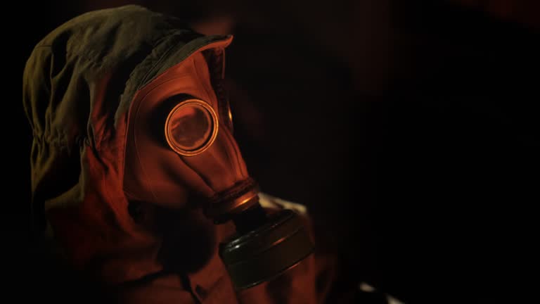 Side view of A person in a gas mask lights a fire of a fire