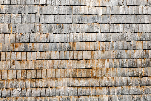 Weathered wooden roof shingles on a wall as creative background