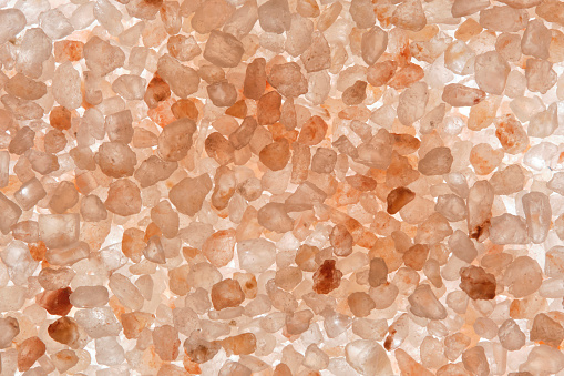 Macro shot of illuminated pink salt against light background, showcasing intricate crystalline structures in delicate hues