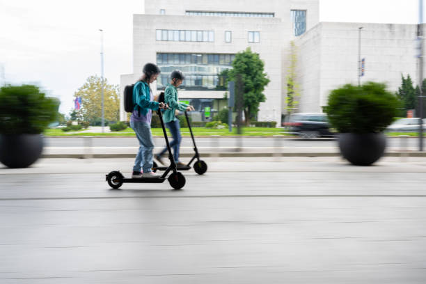 istock Woman and a younger man talking while riding e-scooters to work 2121991240