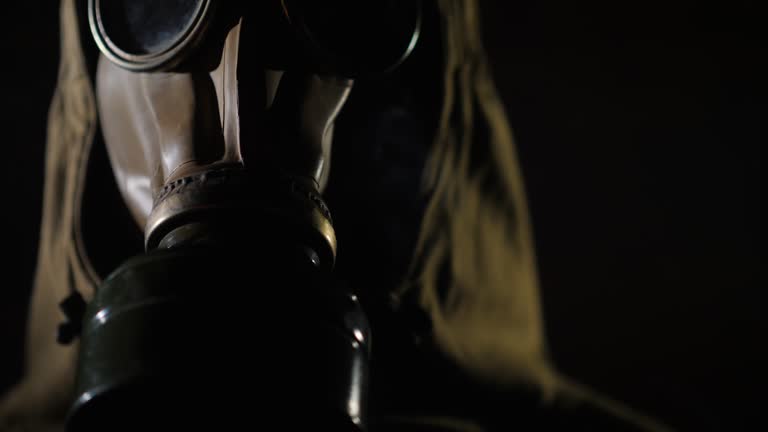 Handheld shot of man in a protective suit and gas mask, smoke in the foreground