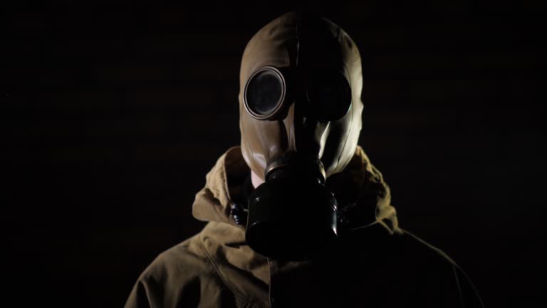 Tilt shot of A man in a protective suit and gas mask on a black background