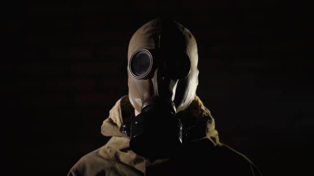 A man in a protective suit and gas mask on a black background