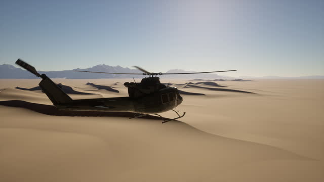 A helicopter flying over a desert with mountains in the background