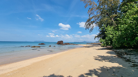 A sandy beach stretching out next to the sparkling ocean under a clear blue sky, creating a serene and picturesque scene. Koh Libong Thailand