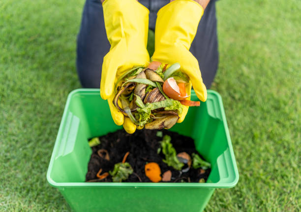 istock Ecology compost supply Kitchen waste recycling composter environmentally friendly. The young man throws leftover fruit peel egg shell and vegetables reduce waste 2122058086