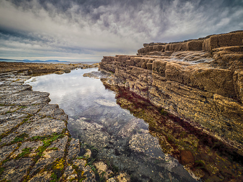 A body of water surrounded by rocks against a cloudy sky at Downpatrick Head, Knockaun, Ballycastle, County Mayo, Ireland.