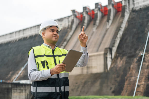 istock Professional asian maintenance engineer man with safety helmet in construction site dam with hydroelectric power plant and irrigation. Manager engineer man working with tablet at project big building. 2122086525