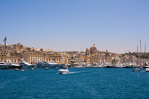 Vittoriosa, Malta - 17 June 2023: Vittoriosa harbor with yachts and boats and the dome of the cathedral in the background