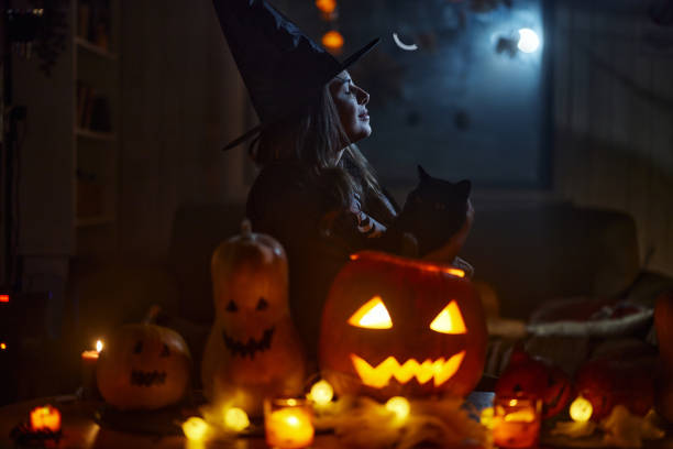 istock Young witch with black cat on Halloween night. 2122104077