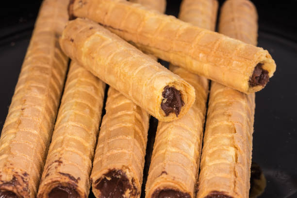 istock Wafer tubes with chocolate cream on black dish close-up 2122111245