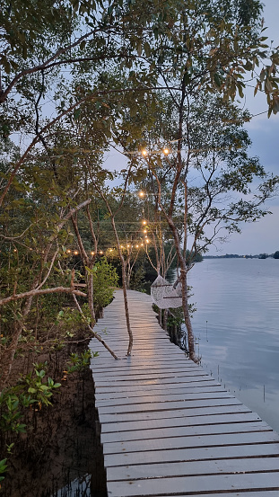 A picturesque wooden walkway winds its way through lush surroundings, leading to a tranquil body of water, inviting visitors to take a peaceful stroll. Chantaburi Thailand