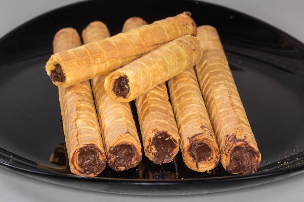 istock Wafer tubes with chocolate cream on black dish close-up 2122119161