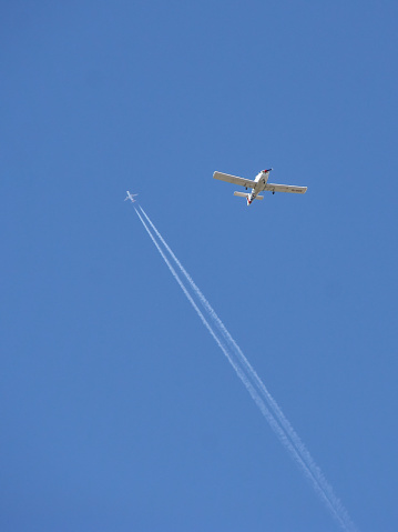Two airplanes various distances and types on the sky. One with vapour trail