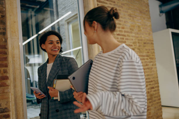 istock Stylish young diverse female employees talk during break time in modern office 2122124388