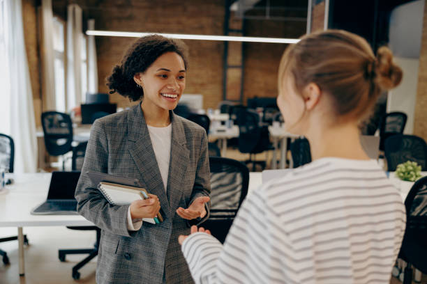 istock Two young diverse business women chatting during work break standing in modern office 2122125950