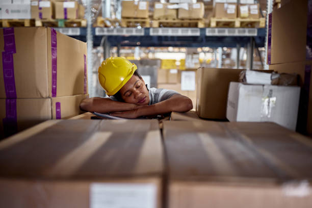 Black female worker taking a nap on packages in storage room.