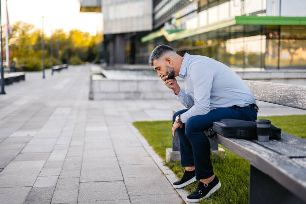 istock Mid-Adult Businessman Feeling Stressed While Sitting On A Bench Outdoors 2122155135